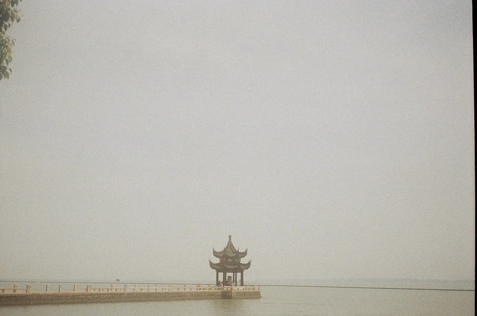 A lone pavilion on a lake pier extending into misty water, evoking a single point of commerce in a vast open landscape of AI platforms.