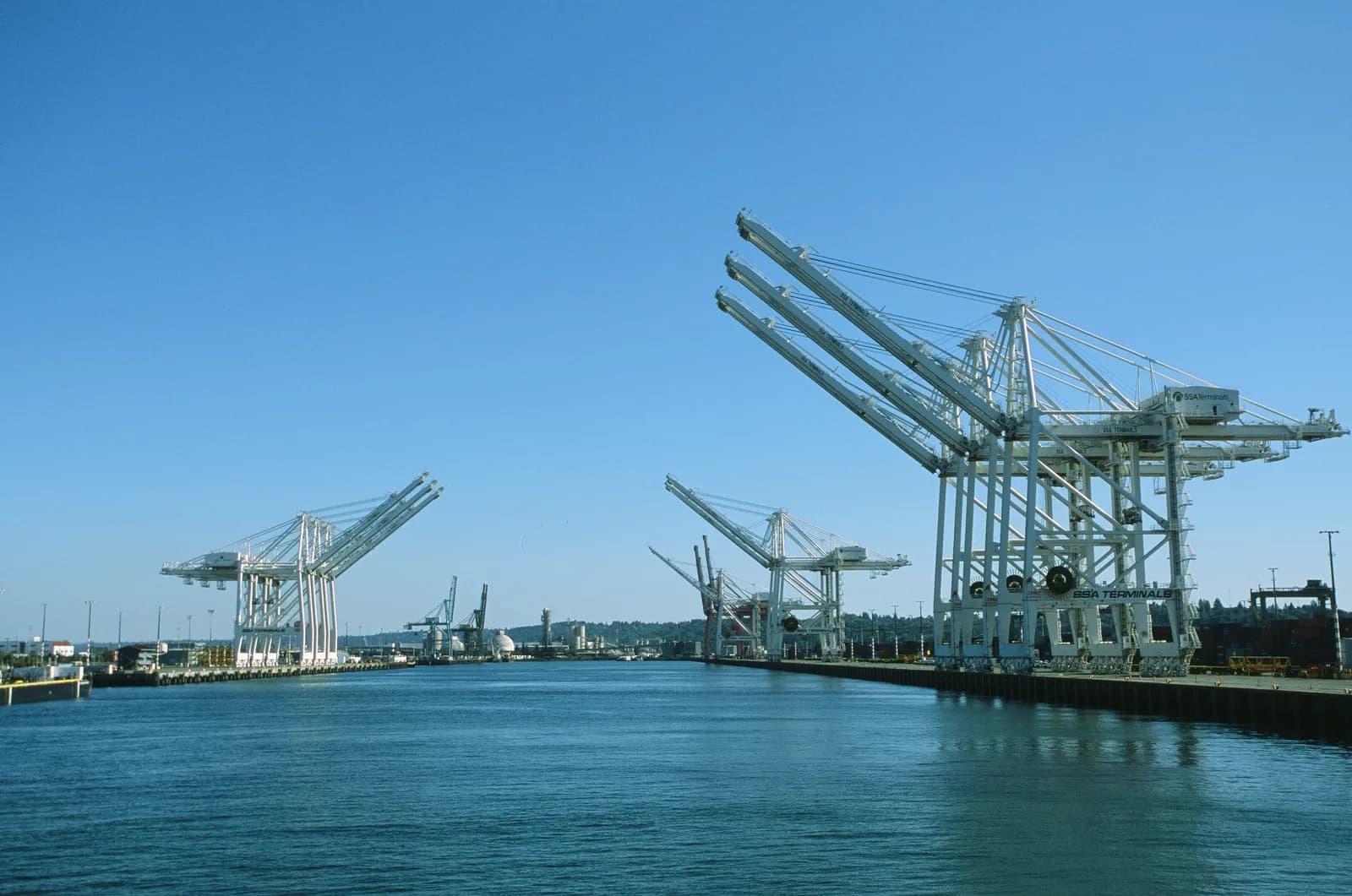 Shipping port with large cranes stretching over calm blue water, representing the infrastructure layer through which brands reach consumers via AI answer engines