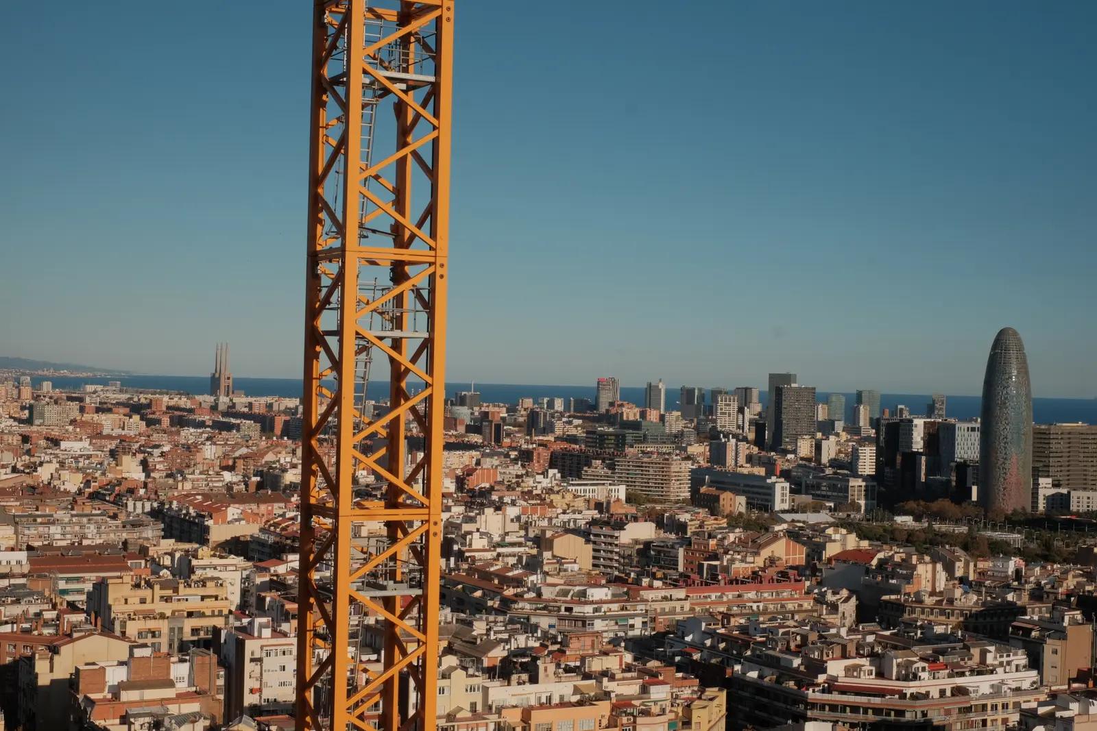 A construction crane rising above Barcelona's cityscape, a visual metaphor for building experimentation infrastructure on top of the existing monitoring layer.
